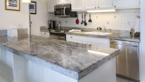 A modern kitchen with granite countertops, stainless steel appliances, and white cabinetry. - Vantage Point #307 2 Bedroom Condo by RedAwning (Vail)
