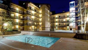 A multi-story hotel with a swimming pool, outdoor lighting, and a brick-paved area. - Vantage Point #307 2 Bedroom Condo by RedAwning (Vail)