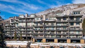 A multi-story apartment building with balconies, parking garage, and a snowy mountain backdrop. - Vantage Point #307 2 Bedroom Condo by RedAwning (Vail)