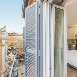 A hotel room with a balcony overlooking a historic cityscape, including a prominent ancient structure. - Trevi s Wish Luxury Suites (Rome)