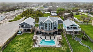 A large two-story house with a swimming pool, multiple decks, and a garage.