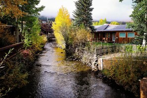 En smal vattenväg omgiven av träd och träkonstruktioner, med en bro i bakgrunden.