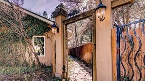 A stone pathway leading to a wooden gate with a metal fence.