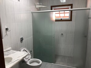A bathroom with a toilet, a sink, and a shower area.