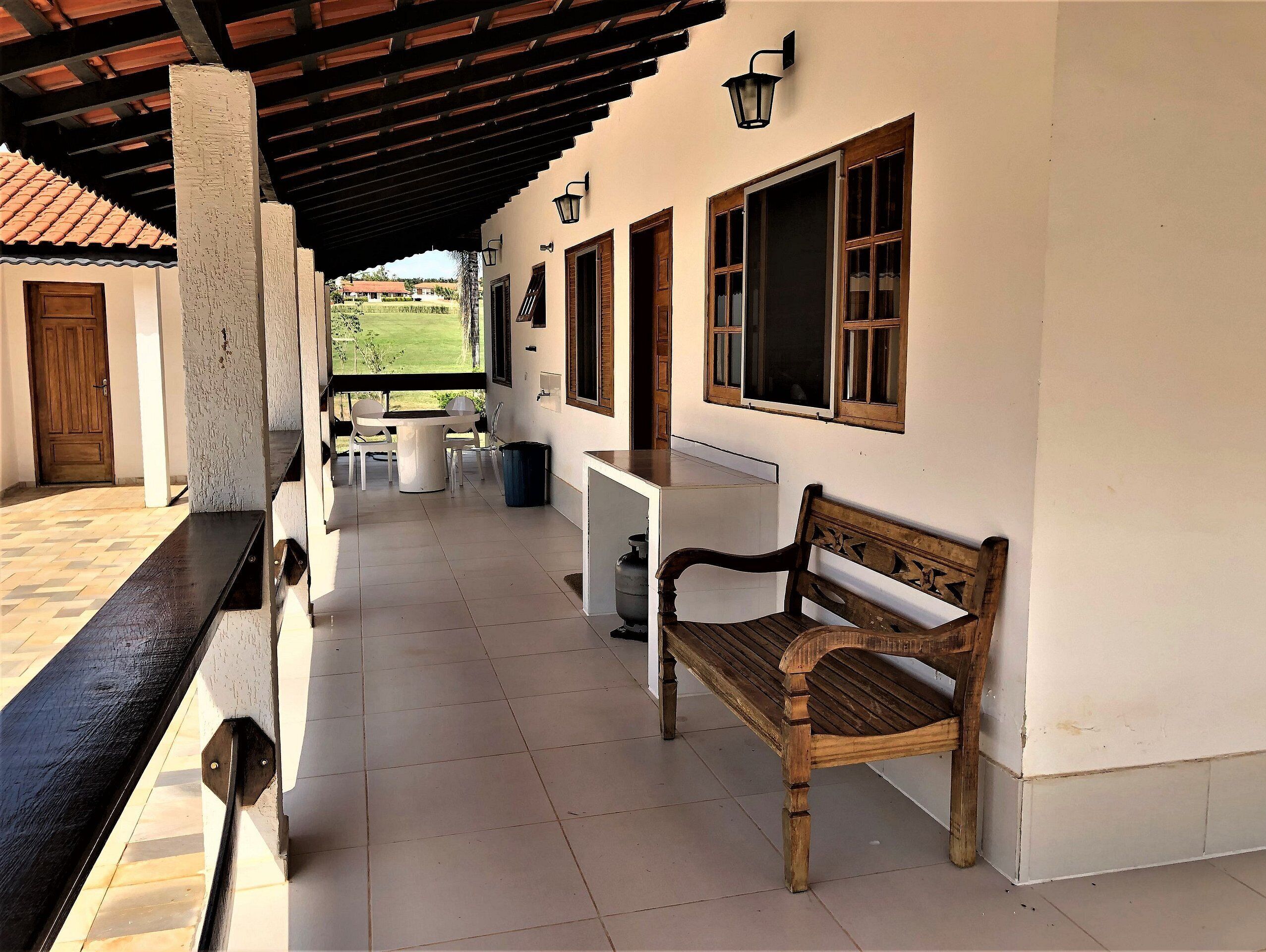 A covered outdoor area with a wooden bench, a table, and chairs.