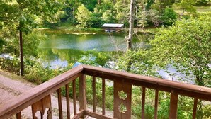 A wooden deck overlooking a lake with boats, surrounded by lush greenery. - Historic Cabin, Peaceful, Waterside, Patio Firepit (Eureka Springs)