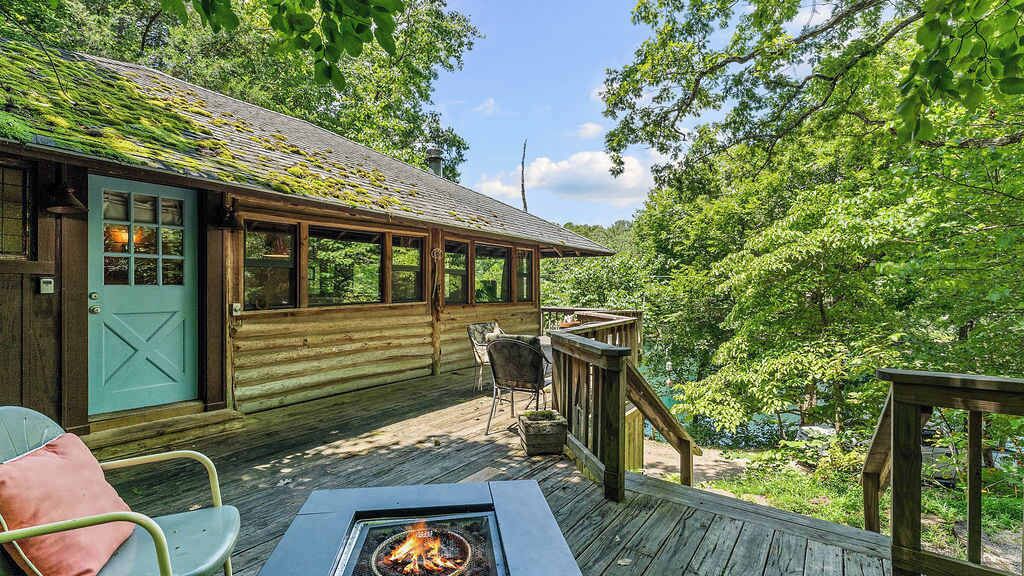 Una baita di legno con veranda, un braciere e vista sulla foresta circostante.