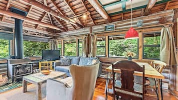 L’intérieur d’une cabane en rondins, avec un canapé, une table à manger et un téléviseur.