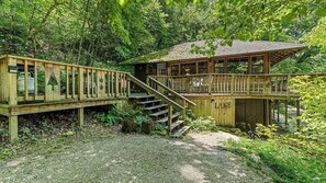 A wooden cabin with a deck and stairs leading to a covered area. - Historic Cabin, Peaceful, Waterside, Patio Firepit (Eureka Springs)