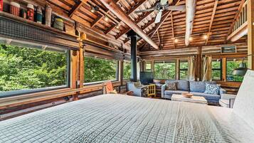 A log cabin interior with a large bed, a sofa, and a fireplace.