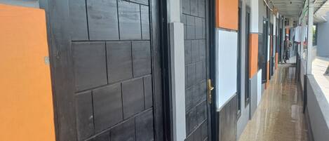 A corridor with doors, a tiled floor, and a metal roof.