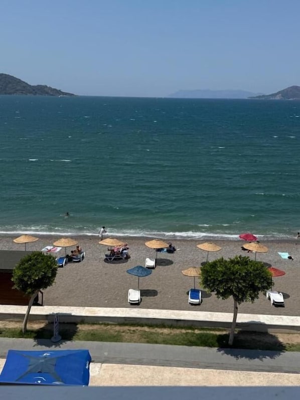 A beach view with umbrellas, lounge chairs, and a clear sky.
