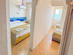 A hotel room with a bed, a nightstand, a mirror, and a window with curtains.