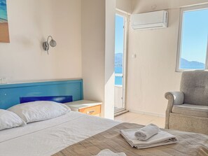 Ein Hotelzimmer mit Bett, Sessel, kleinem Tisch und Klimaanlage.
