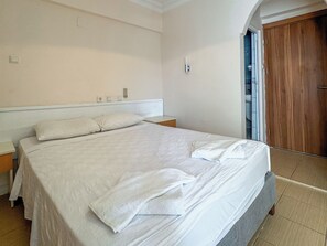 A neatly made bed in a hotel room with a wooden door and a white wall. - Er-Öz Hotel & Restaurant (Fethiye)