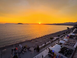 Ein Küsten-Sonnenuntergang mit Uferpromenade, Strand und Restaurants am Meer.