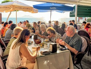 A group of people dining at an outdoor restaurant with a view of the sea. - Er-Öz Hotel & Restaurant (Fethiye)