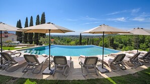 A swimming pool with lounge chairs and umbrellas, surrounded by greenery and a clear sky. - Amazing Villa Chimera Green 10 Pool&Gym  (Arezzo)