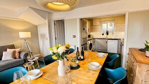 Un comedor moderno con una mesa de madera para cuatro personas, sillas azules y un jarrón con flores.