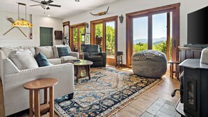 A spacious living room with a sofa, armchairs, a coffee table, and a large rug. There is a fireplace, a ceiling fan, and large windows offering a view of the outdoors. - Welcome to Grandview Lodge! A 4 bedroom, 4 bath Mountain Sanctuary with Mtn View (Nebo)