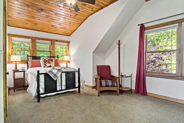 A bedroom with a bed, a chair, a window, and a ceiling fan.