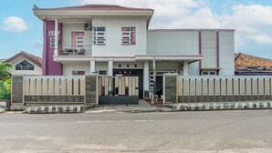 A two-story building with a gated entrance, a balcony on the upper floor, and a visible garage door. - Hotel O Guest House Pahlawan Syariah (Kotabumi)