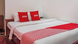 A neatly made bed with white bedding and two red pillows with the word "OYO" on them. - Hotel O Guest House Pahlawan Syariah (Kotabumi)