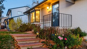 A two-story house with a front porch, a mailbox, and a well-maintained garden with steps leading to the door.