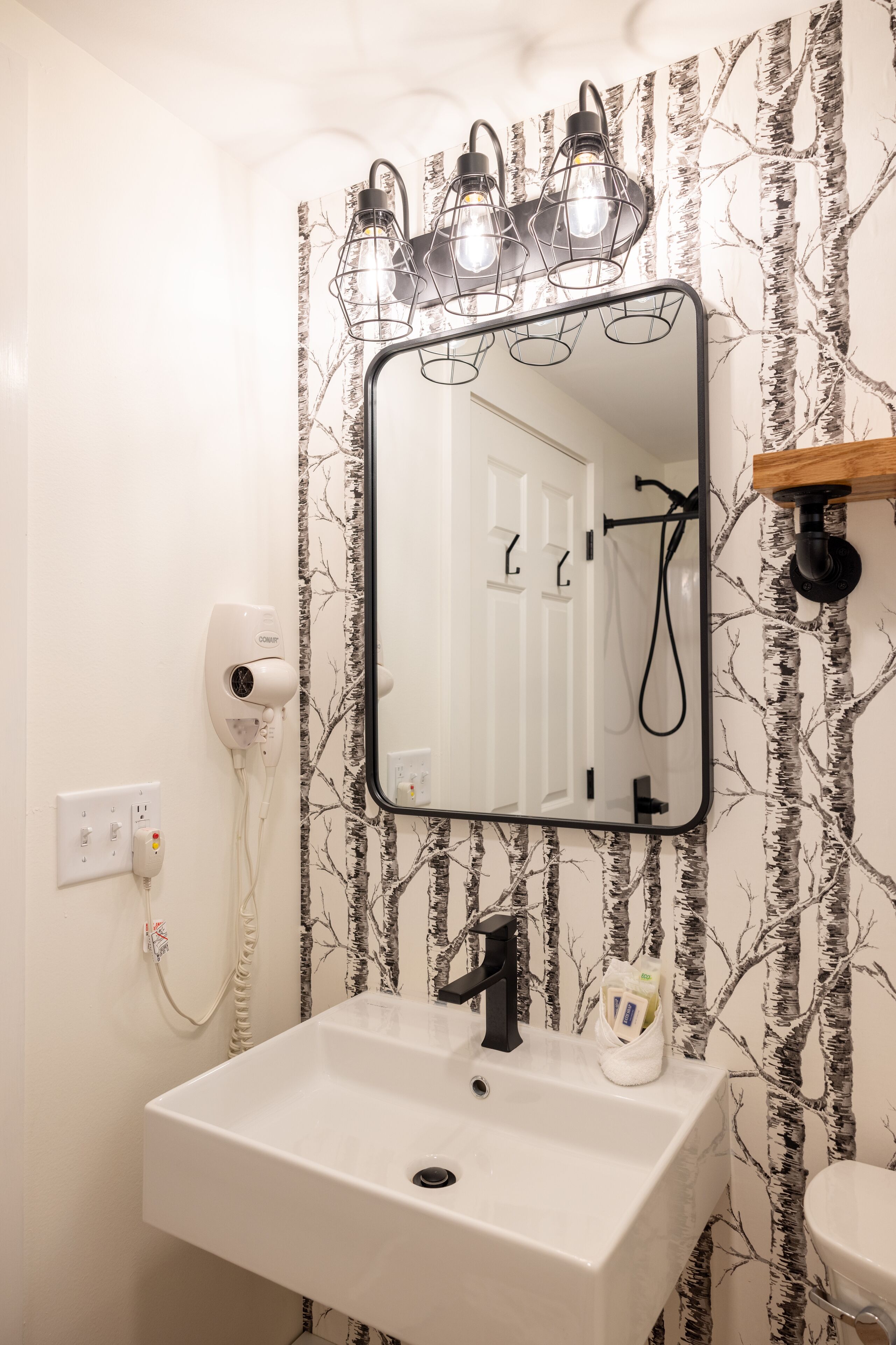 A bathroom with a white sink, a mirror, and a wall-mounted heater.