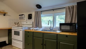 A kitchen with a stove, oven, microwave, sink, and cabinets.