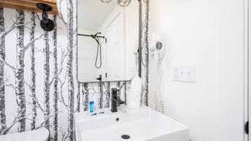 Ein Badezimmer mit einem weißen Waschbecken, einem Spiegel und einem Fön.