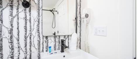 A bathroom with a white sink, a mirror, and a hairdryer.