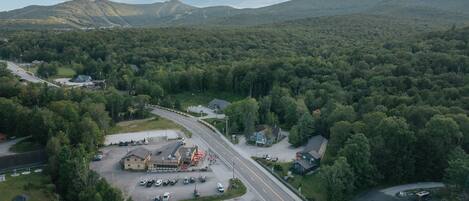 An aerial view of a road leading to a building with a parking lot and a small house nearby.