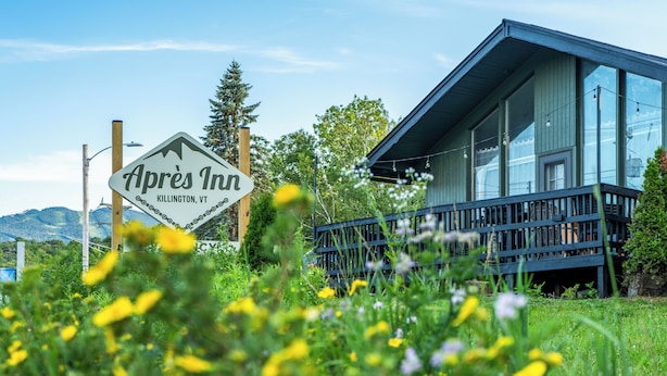 A sign for 'Apres Inn' in KILLINGTON, VT, with a modern building featuring large windows and a balcony.
