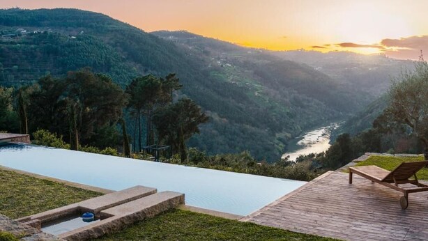 A pool with a wooden deck and a lounge chair overlooking a valley and river. - Javardo Family House  (Marco de Canaveses)