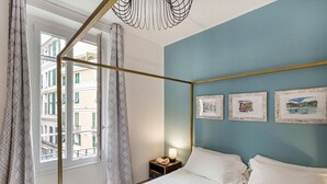 Un dormitorio con una cama, una mesita de noche, una lámpara y tres cuadros en la pared.