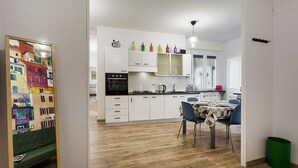 Una cocina moderna con armarios blancos, un horno negro y un comedor con mesa y sillas.