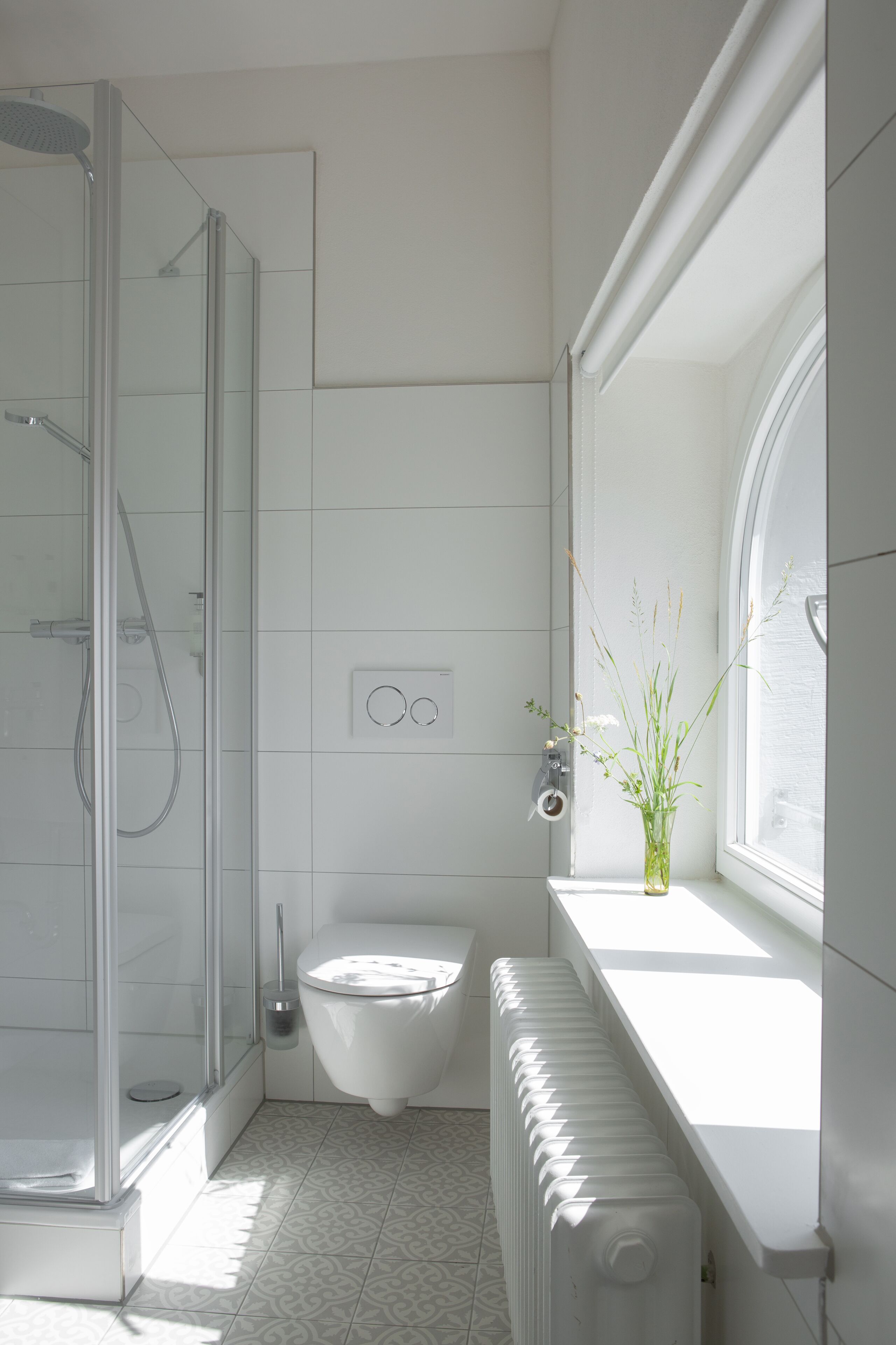 Un baño moderno con cabina de ducha de vidrio, inodoro y radiador.