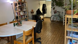 A dining area with a round table, chairs, a bookshelf, a bicycle, and a staircase.