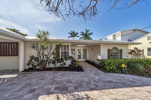 A two-story house with a brick driveway, a covered patio, and a well-maintained garden with palm trees and shrubs. - 3 Bed, 3 Bath, Pool with Hot tub with water view (Sarasota)