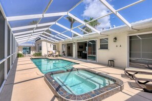 A covered outdoor swimming pool area with a hot tub, lounge chairs, and a patio table. - 3 Bed, 3 Bath, Pool with Hot tub with water view (Sarasota)