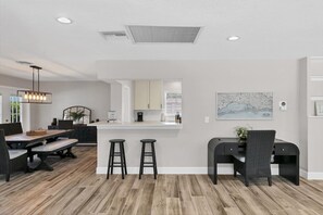 A modern kitchen with white cabinets, a central island, and a dining area with a long table and bar stools. - 3 Bed, 3 Bath, Pool with Hot tub with water view (Sarasota)
