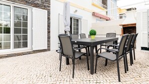 An outdoor patio with a table and chairs, a potted plant, and a brick oven.
