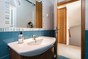 A bathroom with a white sink, wooden cabinets, a mirror, and a striped tile backsplash. - 3 bedroom villa 50 metres from the beach with patio by AlgarveManta (15V3) (Manta Rota)