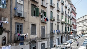 Una strada con auto parcheggiate e un edificio con balconi.