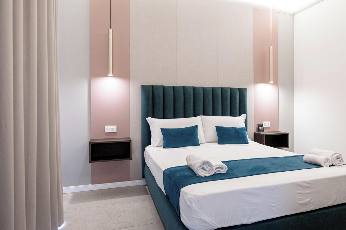 A modern hotel room with a large bed, two bedside tables, and a headboard.