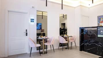 Quarto de hotel com área de jantar, televisão, minibar e espelho.