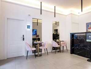 A hotel reception area with a marble counter, a reception desk, and a seating area with chairs. - Museo Suite (Naples)