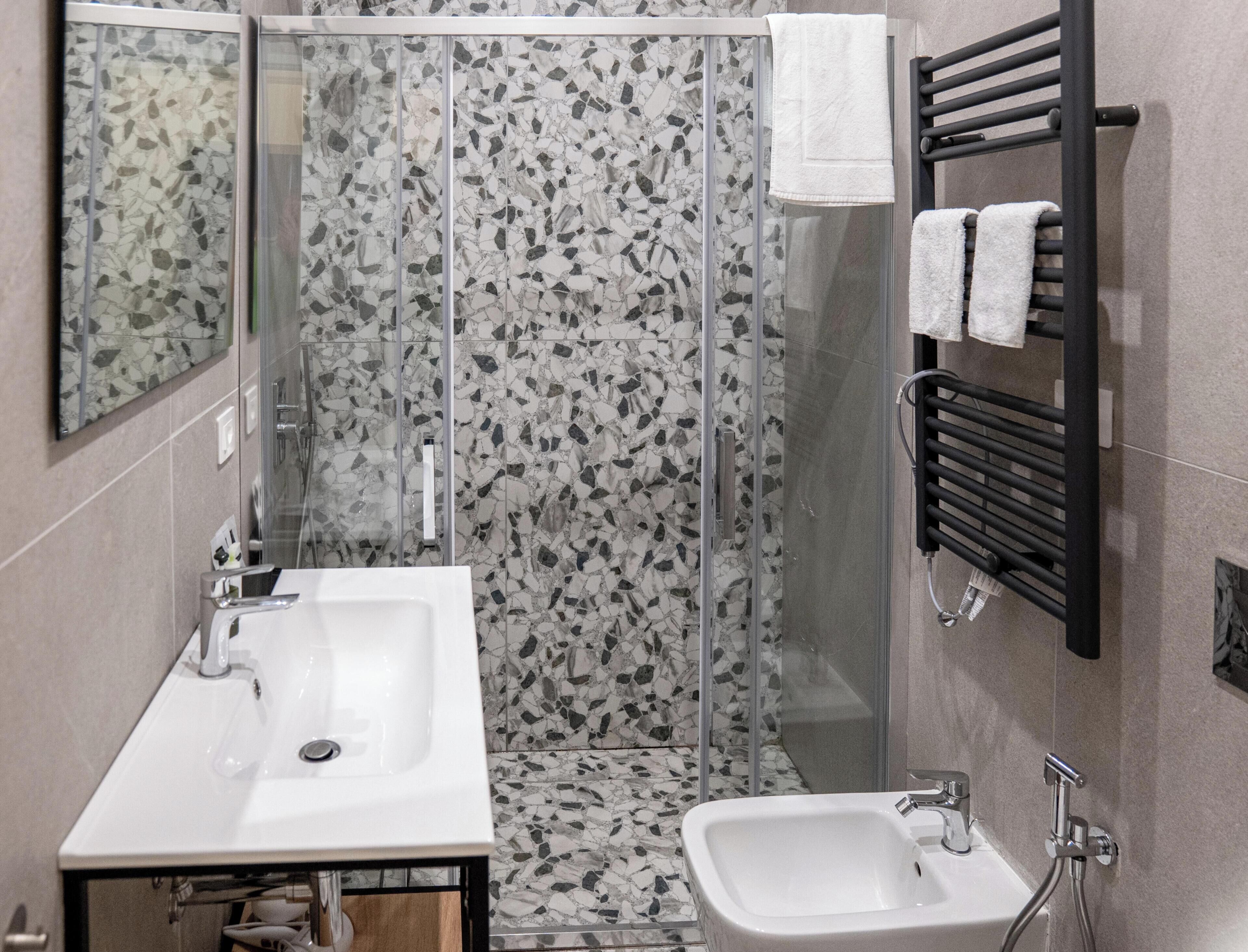 Un baño con ducha envuelta en vidrio, un lavamanos y un bidé.