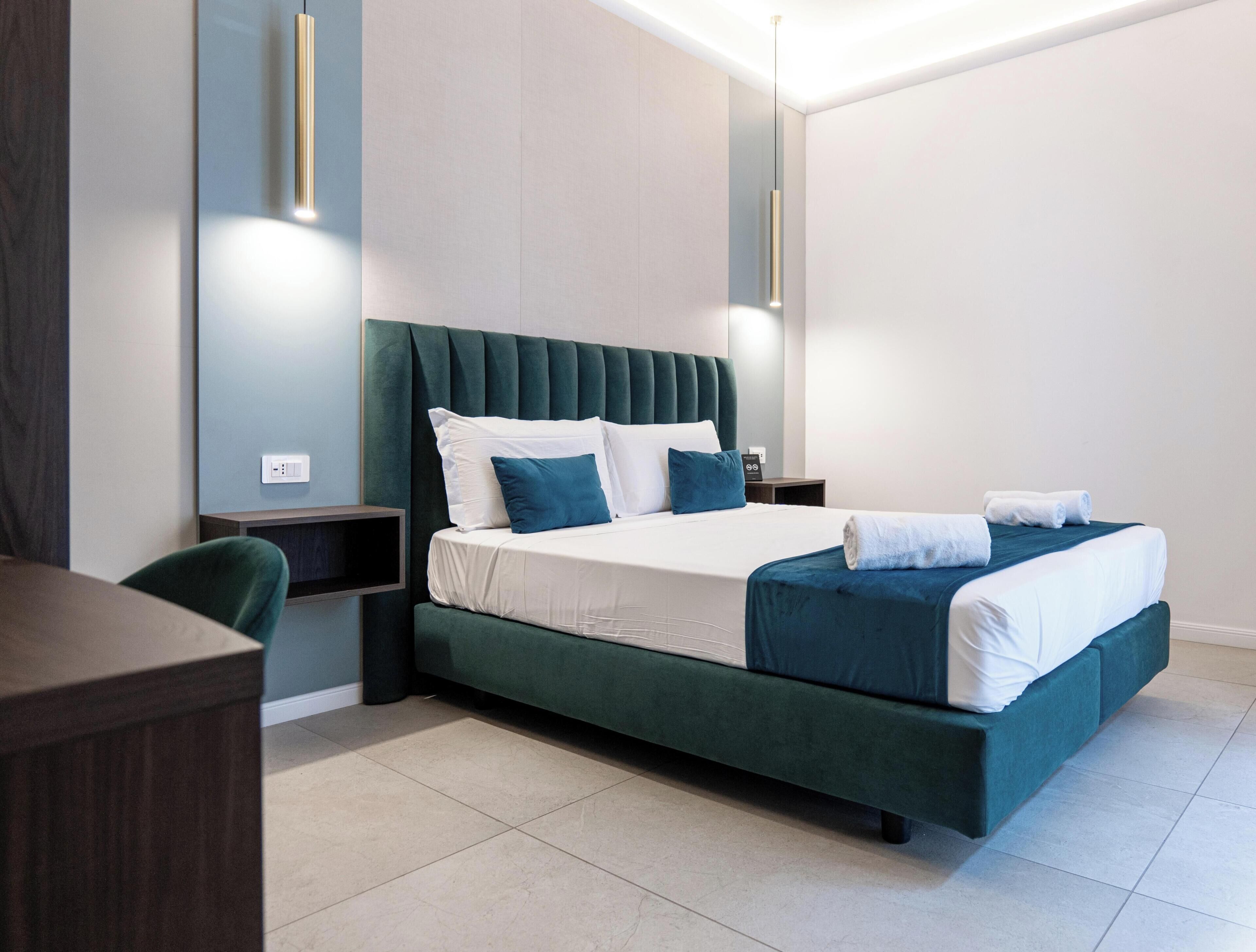 Quarto moderno com cama grande, mesas de cabeceira e escrivaninha.